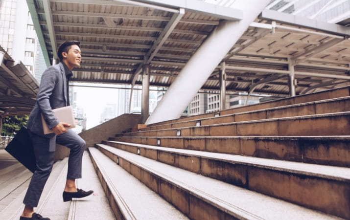 High-paying entry-level jobs for uni grads Man in suit walking up concrete stairs
