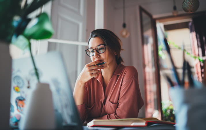 A young woman staring thoughtfully at a laptop