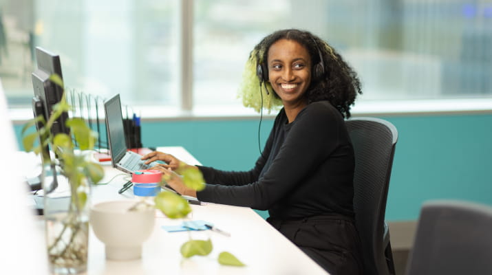 Nabila Jamal smiling at her desk at the Open Universities Australia office